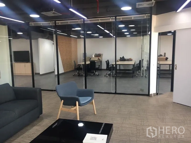Office Space for rent in Sathon, Bangkok - Reception lounge with sofa and armchair facing glass-partitioned meeting rooms under modern lighting.