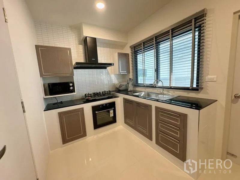 Detached House for rent or sale in Bang Phli, Samut Prakan - Fitted kitchen with gas hob, oven, extractor hood and long window with blinds.