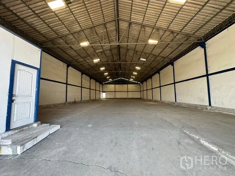 Warehouse for rent in Bang Bo, Samut Prakan - View from the office toward the wide warehouse hall with steel beams and ample floor space.