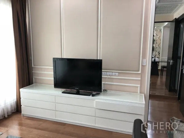 公寓 出租在Pathum Wan, Bangkok - 现代客厅墙面，白色矮柜上摆放电视与软包饰面。