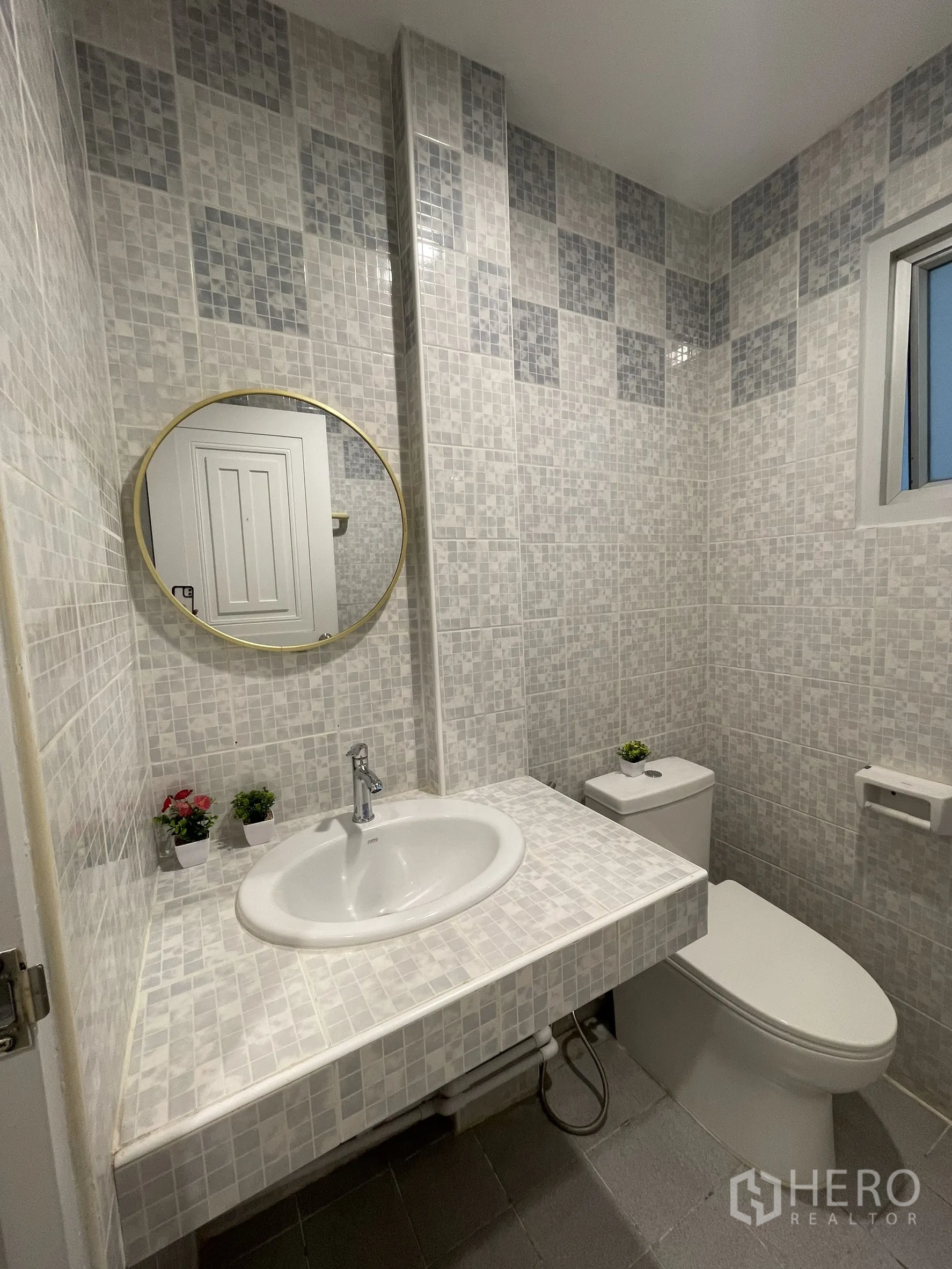 Shophouse for rent in Bang Kapi, Bangkok - Compact bathroom with mosaic wall tiles, round mirror, white basin and toilet.