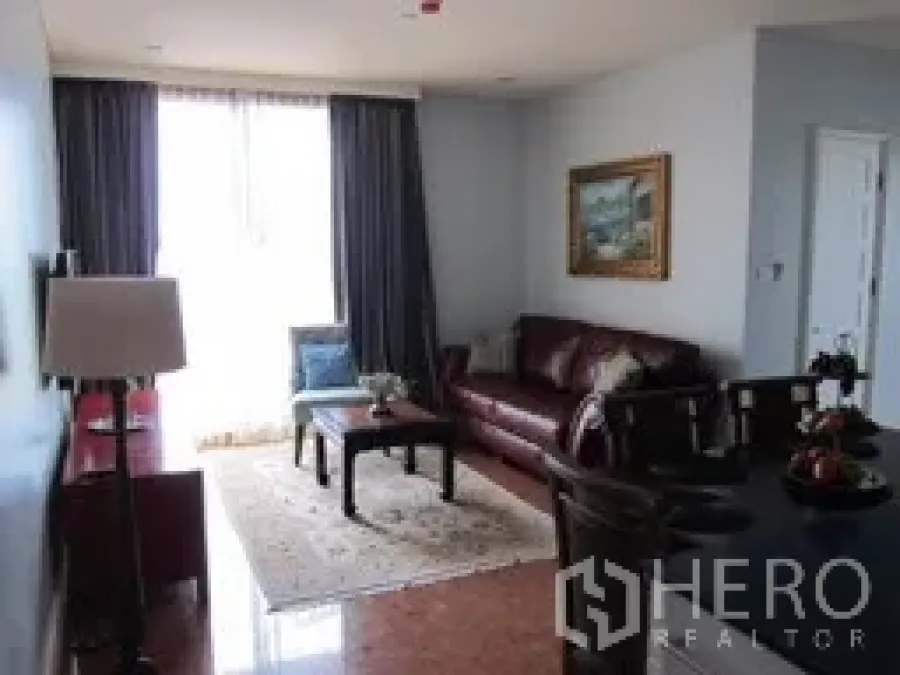 Condominium for rent in Khlong Toei, Bangkok - Bright living and dining area with leather sofa, window drapes, and wall art in a Bangkok condo.