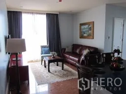 Condominium for rent in Khlong Toei, Bangkok - Bright living and dining area with leather sofa, window drapes, and wall art in a Bangkok condo.