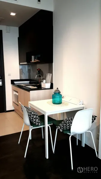 Condominium for rent in Watthana, Bangkok - Compact kitchenette with black countertop and a two‑seat dining table in a modern condo.