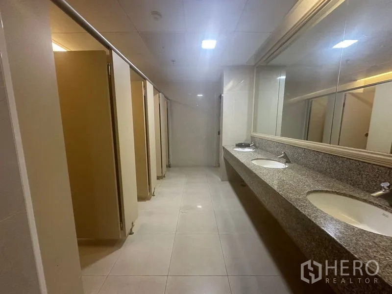 Office Space for rent in Khlong Toei, Bangkok - Clean shared restroom with multiple stalls and granite countertop sinks.