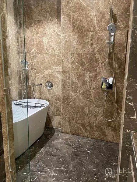 Condominium for rent in Pathum Wan, Bangkok - Marble bathroom featuring a freestanding soaking tub and a glass rain-shower.