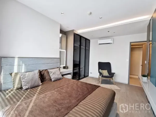 Condominium for rent in Watthana, Bangkok - Spacious master bedroom featuring glass wardrobe, accent chair and air conditioning.