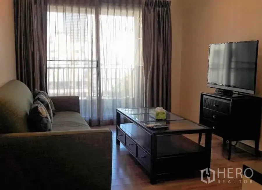 คอนโด ให้เช่าในPathum Wan, Bangkok - ห้องนั่งเล่นสว่างพร้อมหน้าต่างบานใหญ่ ผ้าม่าน ทีวี และโต๊ะกลางกระจก พื้นไม้