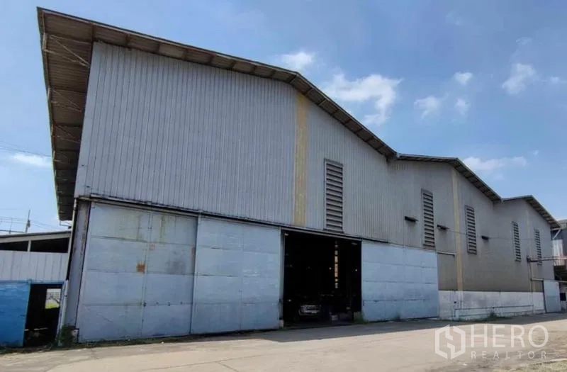 工厂 出租在Krathum Baen, Samut Sakhon - 工业建筑立面，高门与通风百叶，晴空下