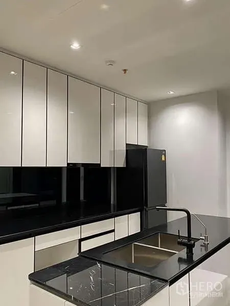 คอนโด ให้เช่า - ชุดครัวยุคใหม่ ตู้บานเงา เคาน์เตอร์หินสีดำ และอ่างล้างจานแบบฝัง