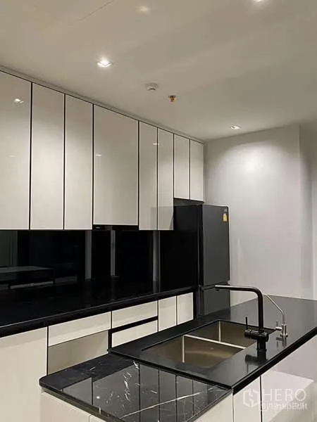 คอนโด ให้เช่า - ชุดครัวยุคใหม่ ตู้บานเงา เคาน์เตอร์หินสีดำ และอ่างล้างจานแบบฝัง