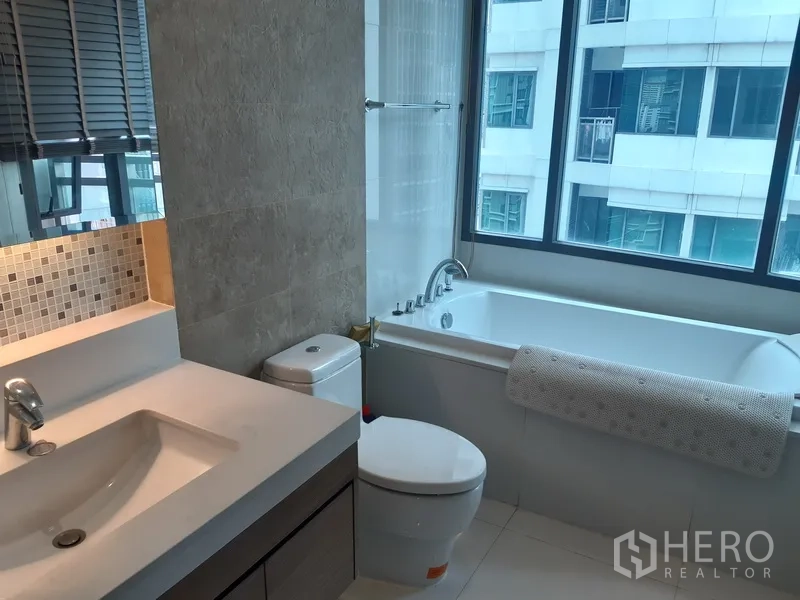 คอนโด ให้เช่าในKhlong Toei, Bangkok - ห้องน้ำร่วมสมัย มีอ่างอาบน้ำริมหน้าต่าง โถสุขภัณฑ์ และอ่างล้างหน้าพร้อมผนังโมเสก