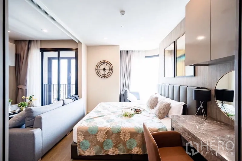 Condominium for rent in Watthana, Bangkok - Cozy bedroom with padded headboard, desk vanity and large windows.