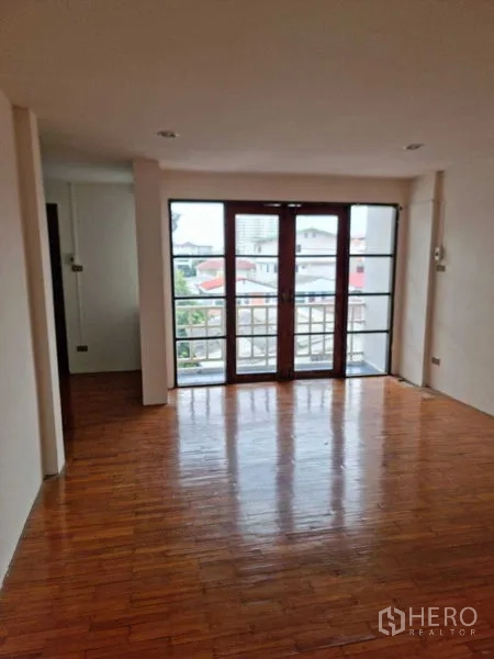 ทาวน์เฮาส์ ให้เช่าในWang Thonglang, Bangkok - พื้นที่นั่งเล่นพื้นไม้มันเงา ประตูกระจกเต็มบานเปิดสู่ระเบียง วิวชุมชนเมือง