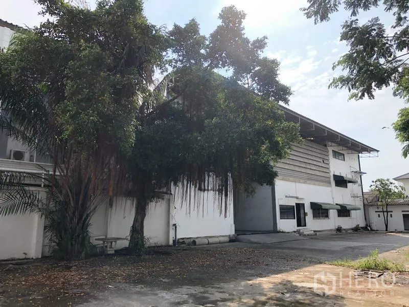 货栈 出租或出售在Bang Kapi, Bangkok - 仓库外立面与宽阔车道、装卸区，绿树成荫。