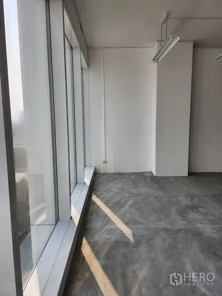 Office Space for rent in Sathon, Bangkok - Bright office corner with full-height glazing and concrete floor allowing natural light along the facade.