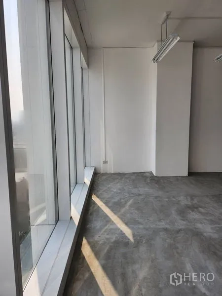 Office Space for rent in Sathon, Bangkok - Bright office corner with full-height glazing and concrete floor allowing natural light along the facade.