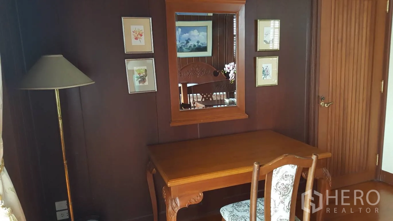 บ้าน ให้เช่าในKhlong Toei, Bangkok - มุมทำงานพร้อมโต๊ะ เก้าอี้ กระจกเงา และกรอบรูป บนผนังไม้เข้ม.