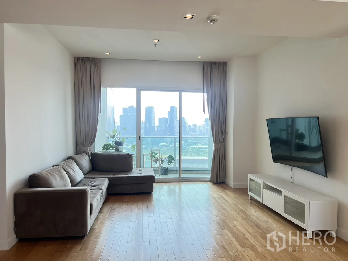 คอนโด for sale in Khlong Toei, Bangkok - ห้องนั่งเล่น โซฟาเข้ามุม ประตูกระจกสู่ระเบียง วิวเมืองและสวน