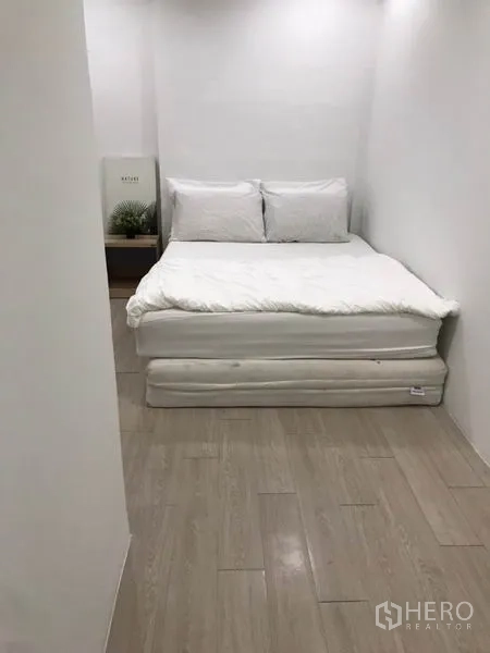 带办公室的家 出租 - 紧凑卧室，白色床铺、浅木地板与极简装饰。