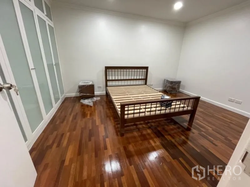 คอนโด ให้เช่าในKhlong Toei, Bangkok - ห้องนอนรอง พื้นไม้เงา เตียงไม้ และตู้เสื้อผ้าติดผนัง