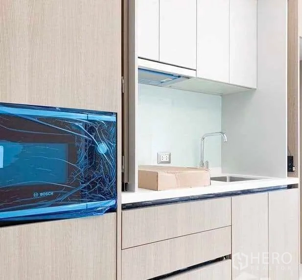 公寓 出售在Ratchathewi, Bangkok - 现代一体化小厨房，浅木色橱柜、台上水槽与嵌入式博世微波炉。