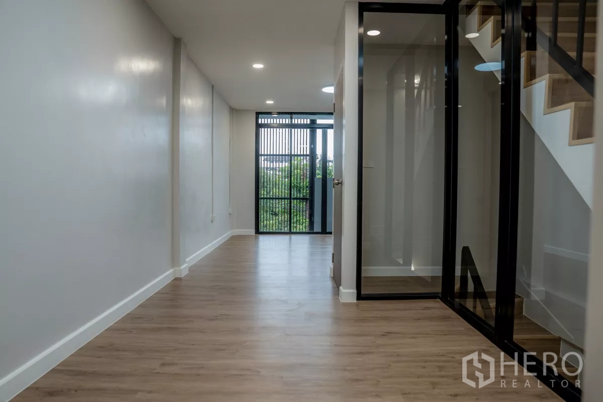 ทาวน์เฮาส์ ขายในWatthana, Bangkok - โถงยาวติดไฟดาวน์ไลท์เชื่อมออกระเบียง กั้นบันไดด้วยผนังกระจก