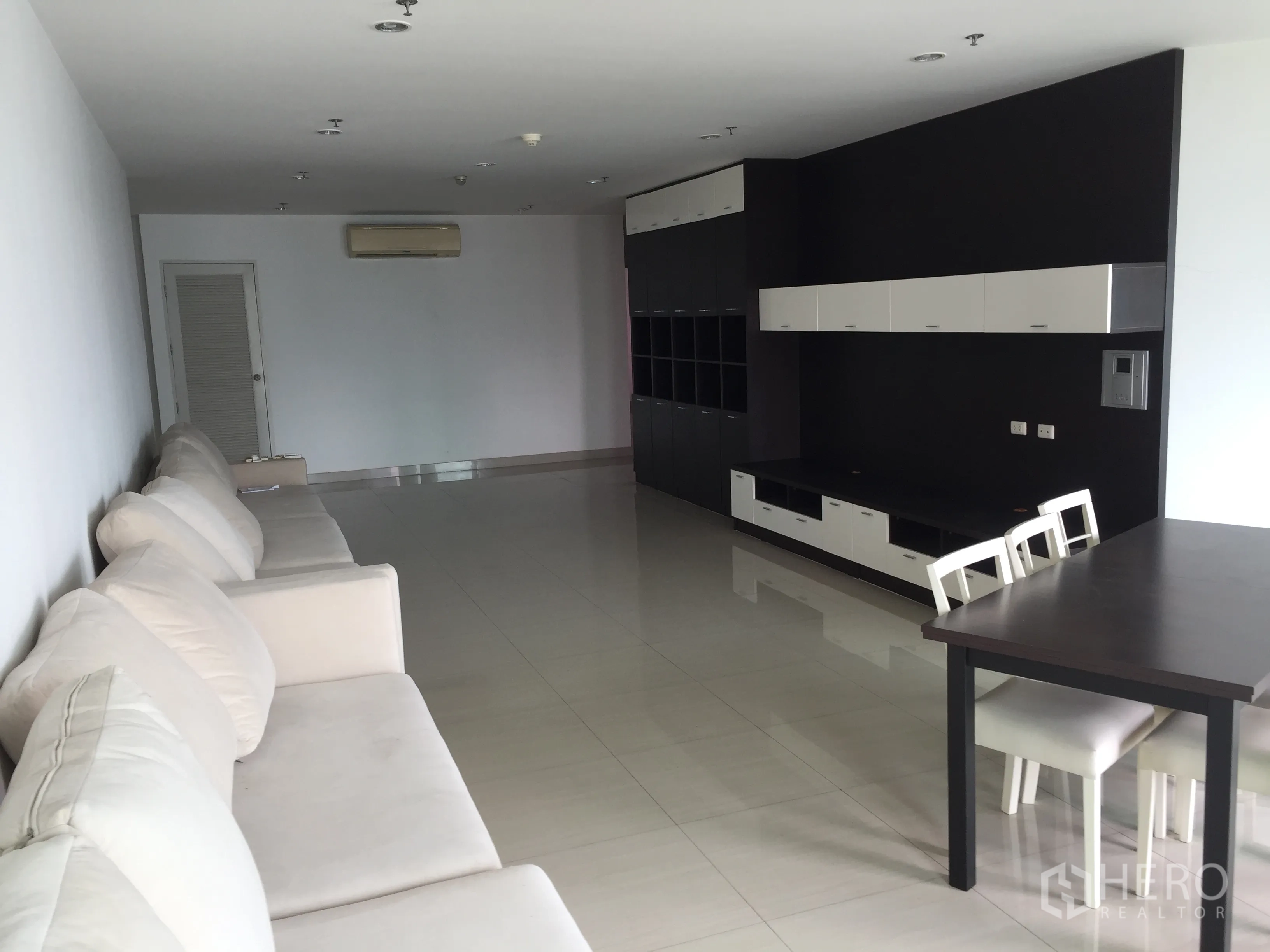 คอนโด ให้เช่าหรือขายในWatthana, Bangkok - โซนรับแขกเปิดโล่ง โซฟาสีครีมตัวยาว และตู้บิวท์อินสีดำขาว