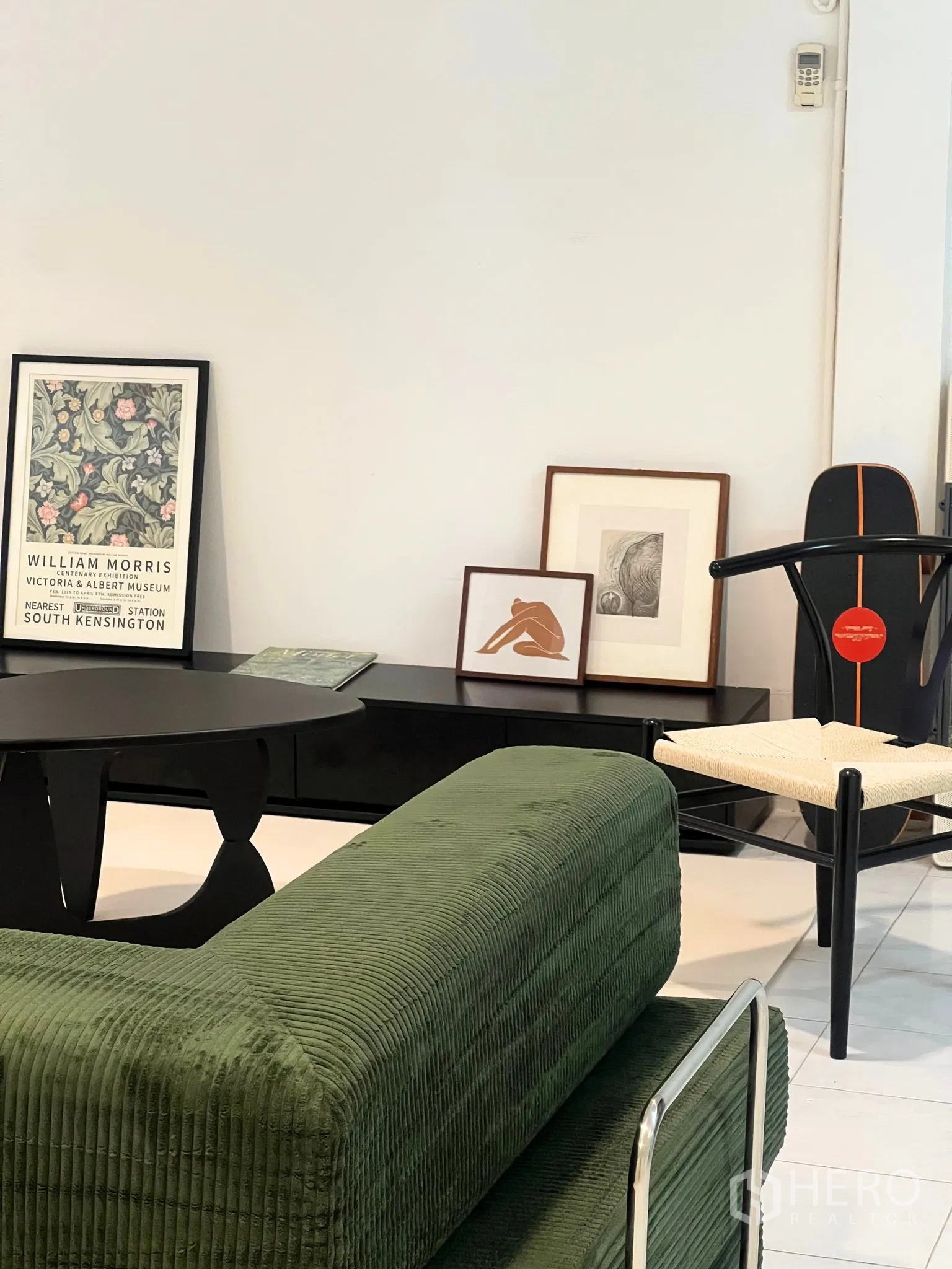 ทาวน์เฮาส์ ให้เช่า - มุมนั่งเล่นอบอุ่น โซฟาผ้าลอนสีเขียว ตู้วางทีวีสีดำ และงานศิลป์