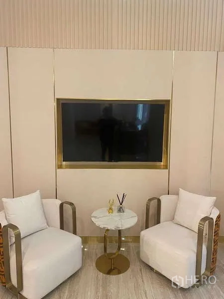 Office Space for rent in Huai Khwang, Bangkok - Contemporary reception lounge with wall-mounted TV, marble side table and two white armchairs in a Bangkok office.