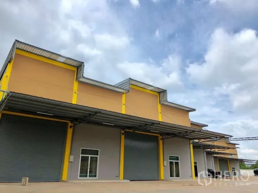 โรงงาน ให้เช่าในMueang Samut Sakhon, Samut Sakhon - อาคารโรงงานสมัยใหม่โทนเหลือง มีประตูม้วนขนาดใหญ่และหลังคาคลุมจุดขนถ่าย