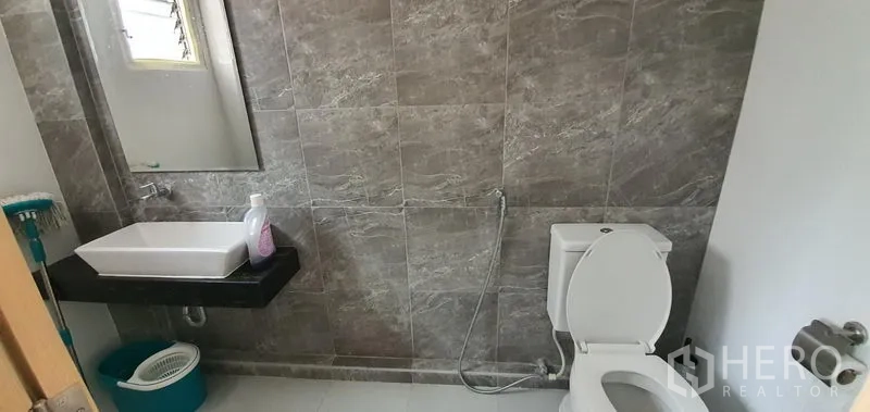 Home Office for rent in Khlong Toei, Bangkok - Modern bathroom with gray stone-look tiles, countertop basin and toilet.