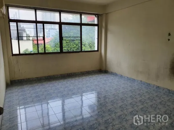 Shophouse for rent in Bang Rak, Bangkok - Bright upper room with large windows overlooking trees and city buildings.