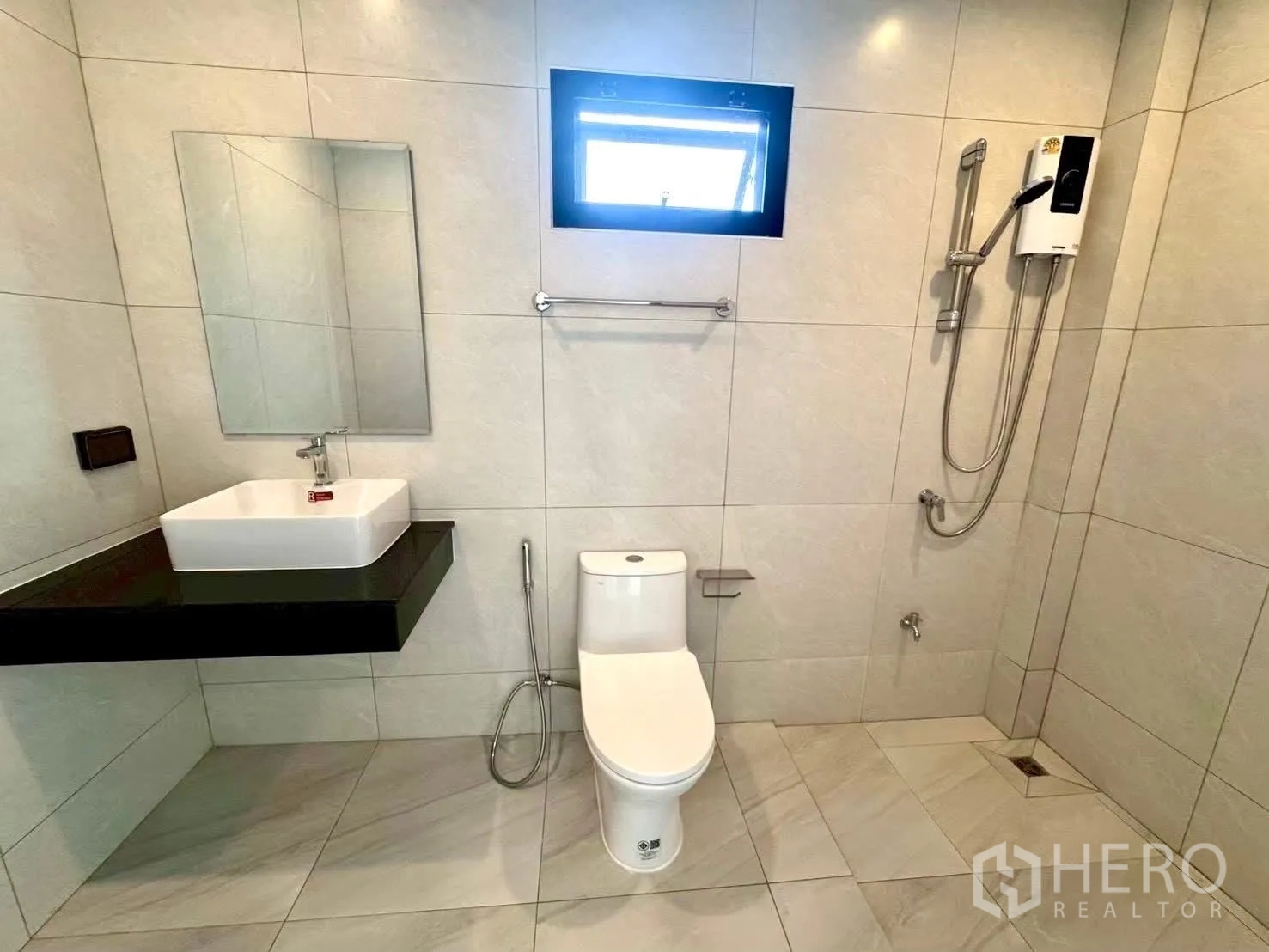 Home Office for rent in Wang Thonglang, Bangkok - Modern bathroom with vanity, toilet, towel rail, window, and walk-in shower with water heater.