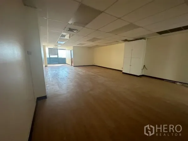 Office Space for rent - Long open workspace with ceiling panels, neutral walls and full-height windows letting in natural light.