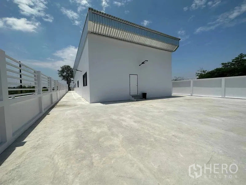 คลังสินค้า ขายในKhlong Luang, Pathum Thani - ลานคอนกรีตด้านหลังล้อมรอบโกดังสีขาว พร้อมประตูบริการด้านข้าง