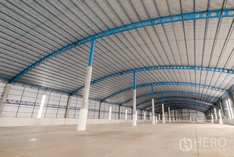 Warehouse for rent in Ban Pho, Chachoengsao - High arched-roof warehouse showing daylight wall panels and multiple support columns.