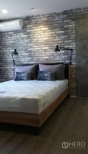 คอนโด ให้เช่าหรือขายในWatthana, Bangkok - ห้องนอนอบอุ่นผนังอิฐโชว์แนว เตียงไม้ โคมไฟหัวเตียง และเครื่องปรับอากาศ