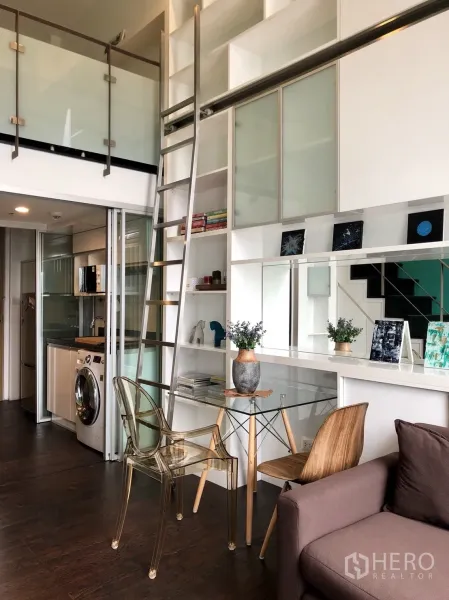 คอนโด ให้เช่าหรือขายในKhlong Toei, Bangkok - โถงรับแขกเพดานสูง มีชั้นบิวท์อิน บันไดเลื่อน โต๊ะกินข้าวกระจก และครัวพร้อมเครื่องซักผ้า