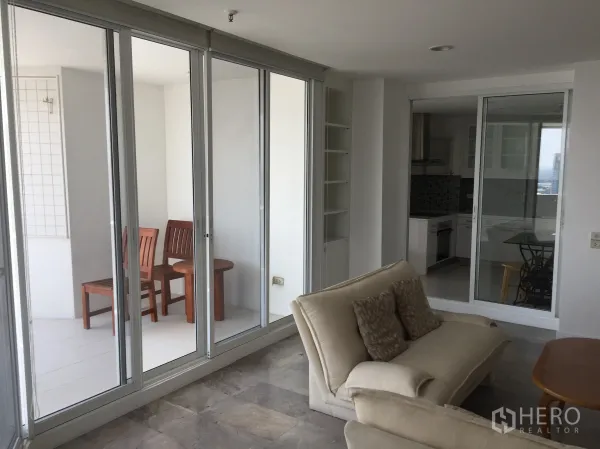 คอนโด ให้เช่าในWatthana, Bangkok - ห้องนั่งเล่นเปิดออกสู่ระเบียงกระจกพร้อมชุดที่นั่ง และครัวแยก