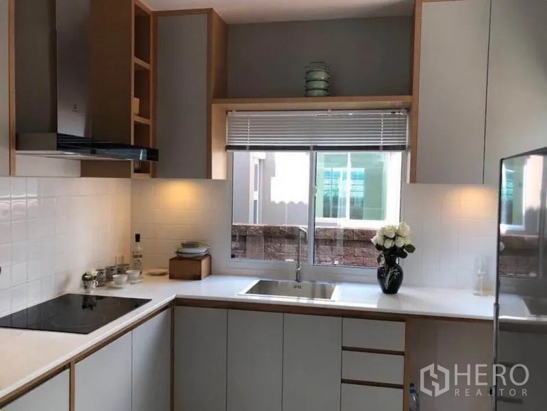 บ้าน ให้เช่าในSuan Luang, Bangkok - ครัวรูปตัวแอล เคาน์เตอร์สีขาว เตา เครื่องดูดควัน และหน้าต่างเหนืออ่างล้างจาน