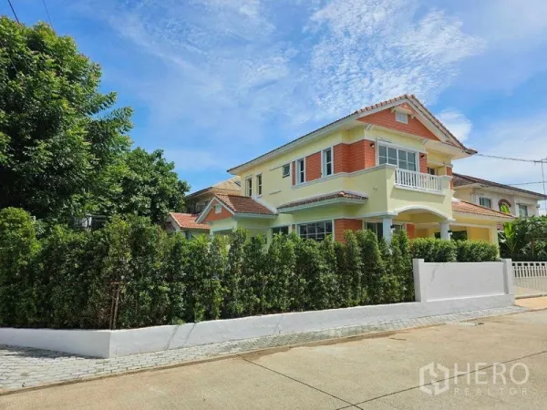 Detached House for rent in Thanyaburi, Pathum Thani - Corner view of the detached house with privacy hedge and bright facade on a quiet street in Thanyaburi.