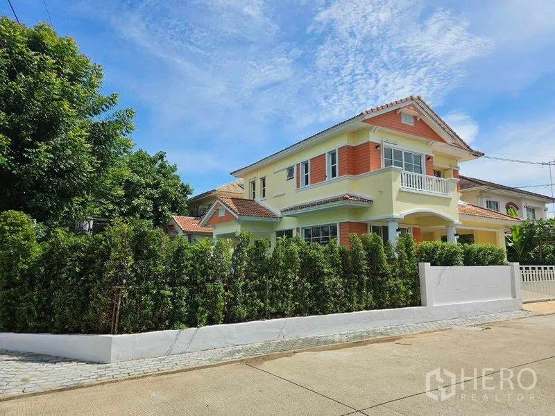 Detached House for rent in Thanyaburi, Pathum Thani - Corner view of the detached house with privacy hedge and bright facade on a quiet street in Thanyaburi.