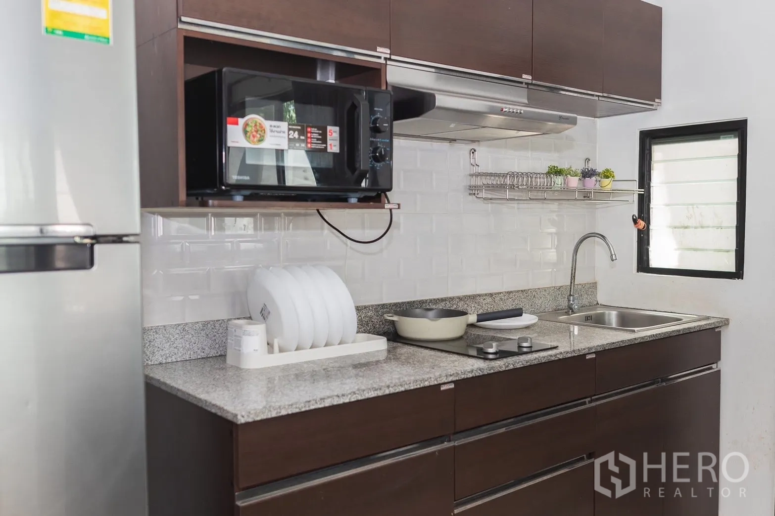 Townhouse for rent in Bang Phli, Samut Prakan - Kitchen close-up showing granite countertop, sink, stove, and microwave.
