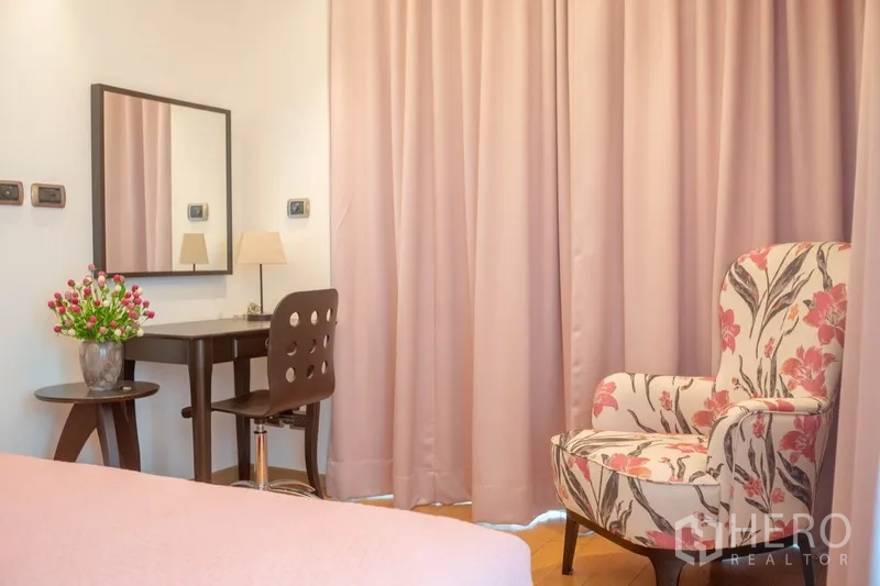 คอนโด ให้เช่าในPhaya Thai, Bangkok - มุมห้องนอนพร้อมโต๊ะทำงาน กระจก และเก้าอี้ลายดอกใกล้ผ้าม่าน