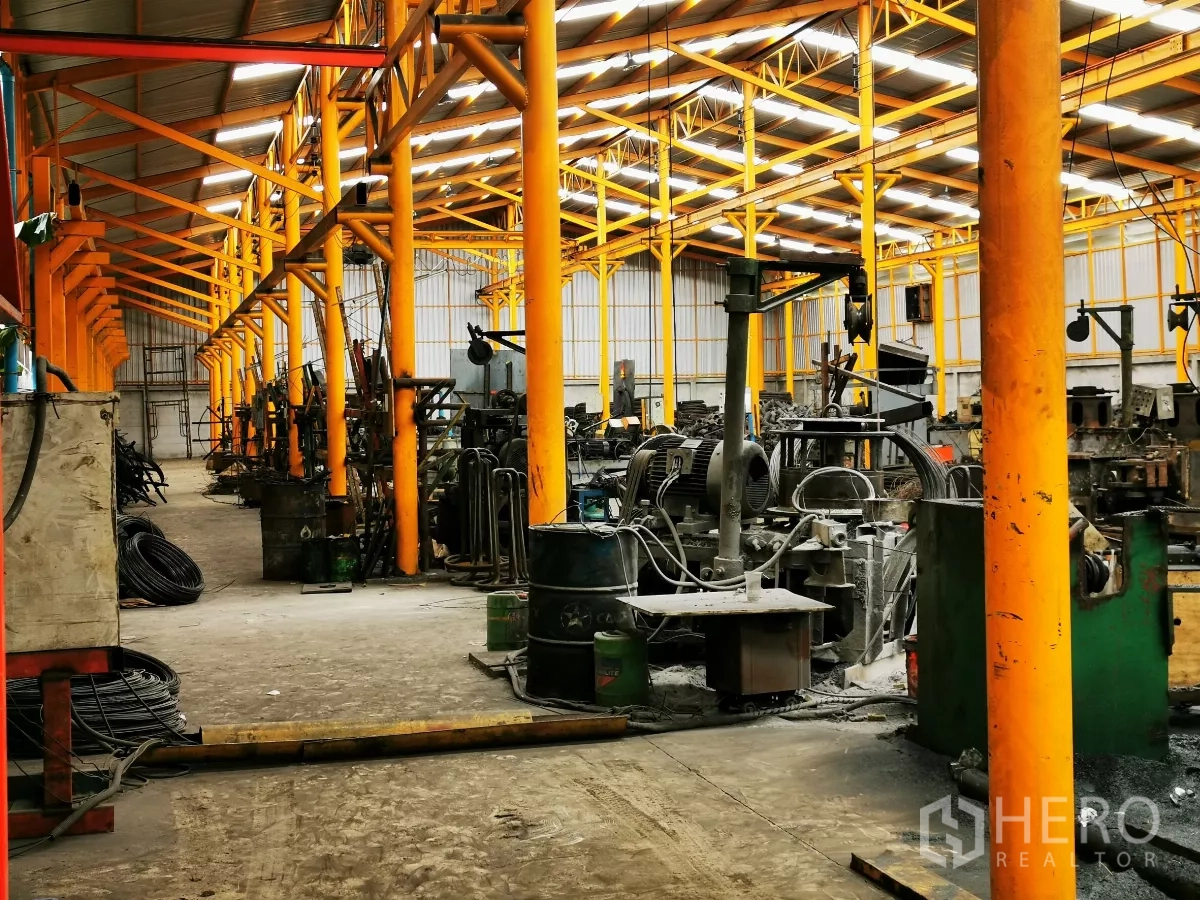 工厂 出售在Bang Bua Thong, Nonthaburi - 生产区配备重型机械，高挑屋顶与黄色钢梁。