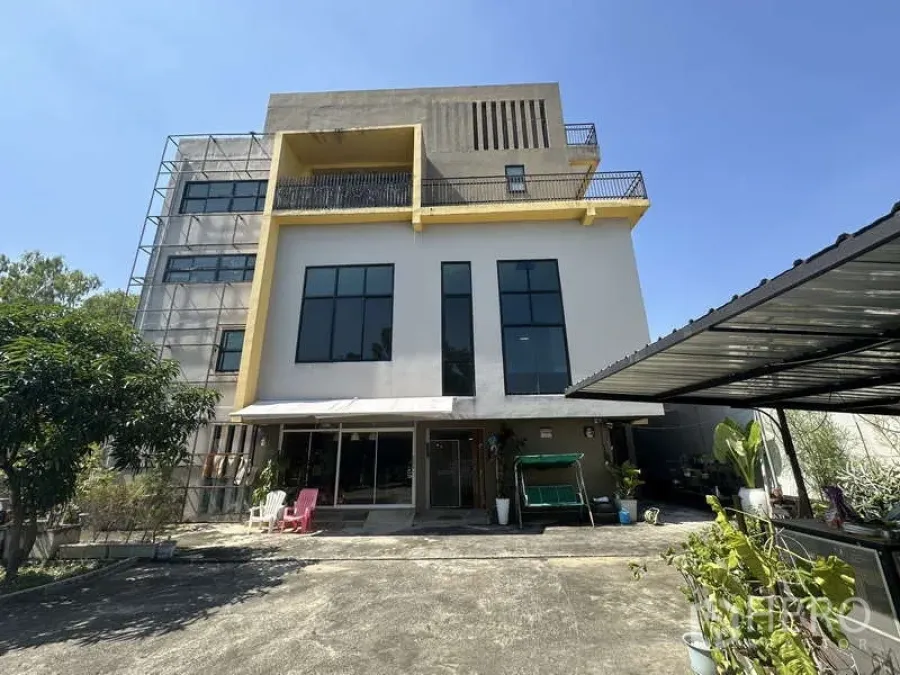Home Office for sale in Lam Luk Ka, Pathum Thani - Multi-storey home office facade with tall windows, balcony and covered carport in Lam Luk Ka under a clear sky