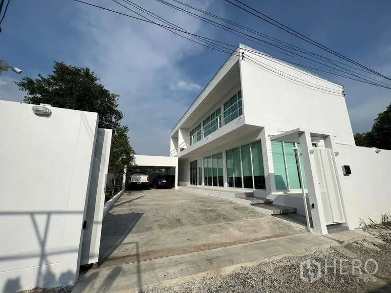 บ้าน ให้เช่าในLat Krabang, Bangkok - มุมมองด้านหน้าบ้านเดี่ยวสีขาวสมัยใหม่ พร้อมทางวิ่งรถกว้าง