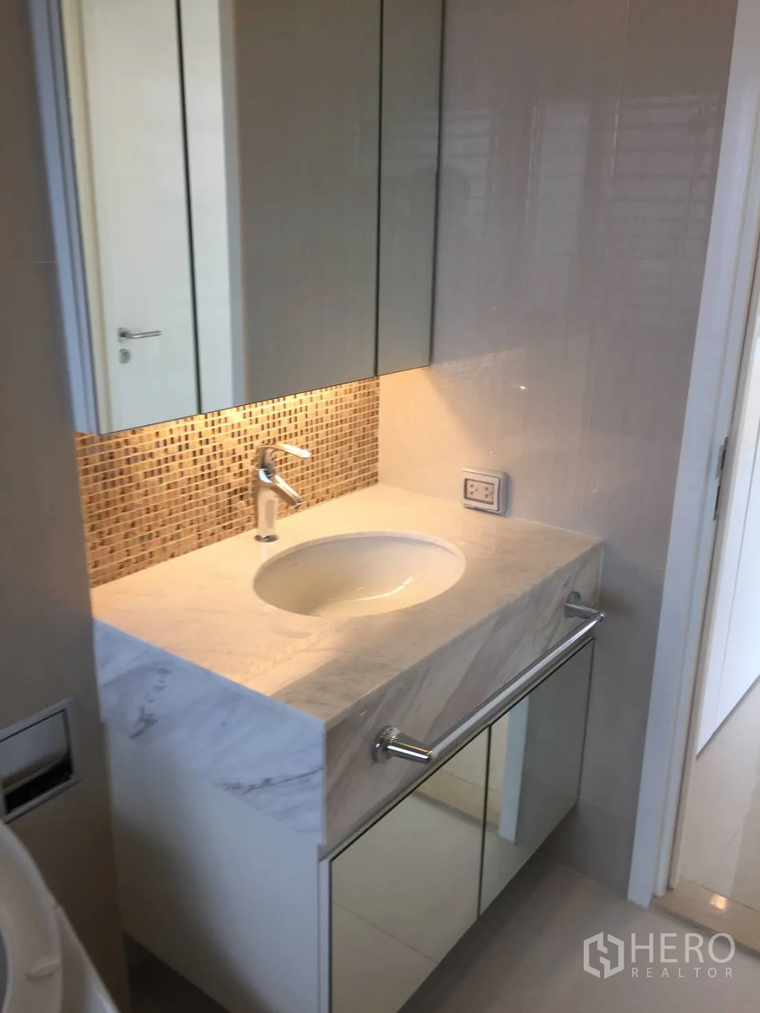 Condominium for rent or sale in Ratchathewi, Bangkok - Bright bathroom with marble vanity, mirrored cabinets, and mosaic backsplash.