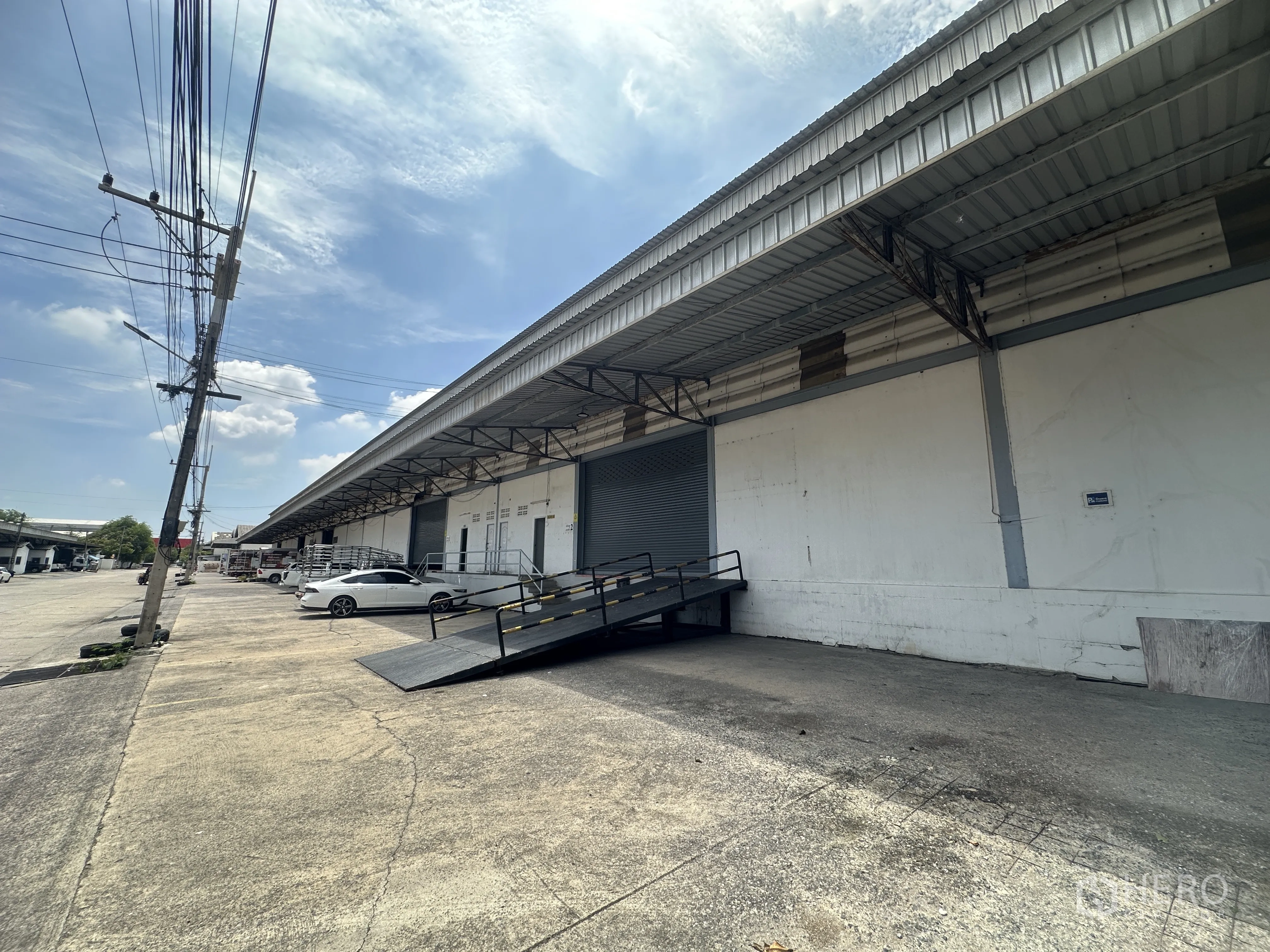仓库 for rent in Khlong Luang, Pathum Thani - 外部装卸区，带雨棚的升高月台、金属坡道与停车区域。